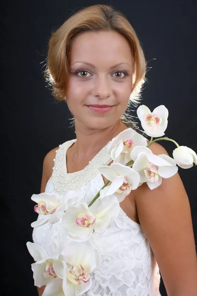 Mulher atraente com orquídea sobre fundo escuro — Fotografia de Stock