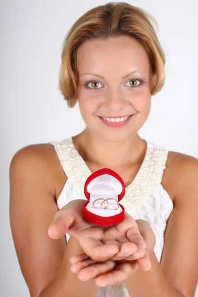 Kobieta trzyma obrączki w czerwonym polu. skupić się na pierścienie — Zdjęcie stockowe