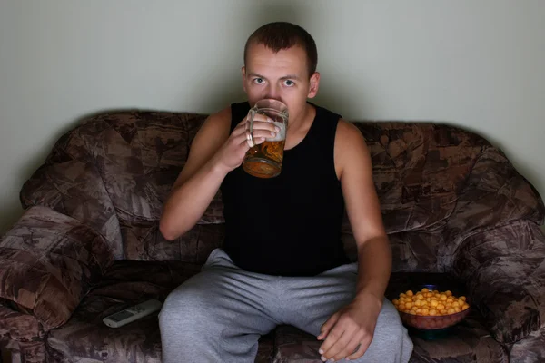 Мужчина смотрит телевизор и пьет пиво — стоковое фото