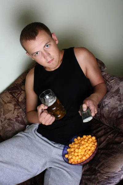Uomo, guardando la tv con birra e patatine fritte — Foto Stock