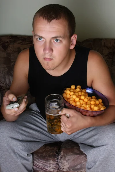 Άνθρωπος βλέποντας τηλεόραση με μπύρα και τηγανιτές πατάτες — Φωτογραφία Αρχείου