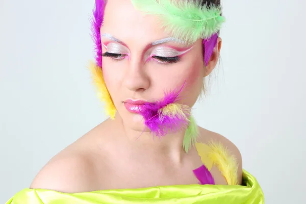 Kvinna med creative make-up och fjädrar — Stockfoto