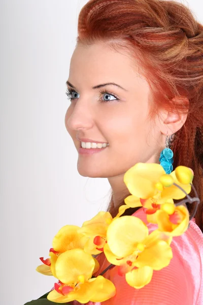 Rödhårig kvinna med gul orkidé — Stockfoto