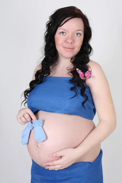 Mulher grávida em material azul com borboleta e bebê meias — Fotografia de Stock