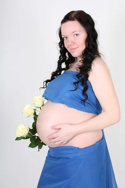 Kobieta w ciąży w niebieski materiał z różami — Zdjęcie stockowe