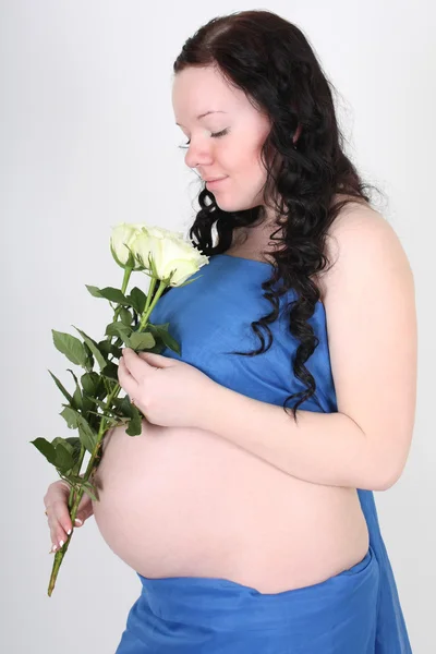 Mulher grávida em material azul com rosas — Fotografia de Stock