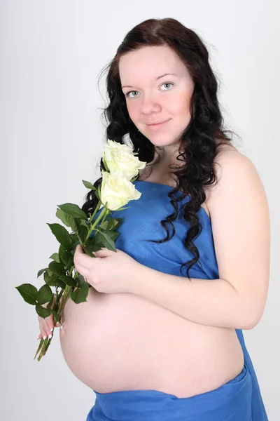 Zwangere vrouw in blauwe materiaal met rozen — Stockfoto