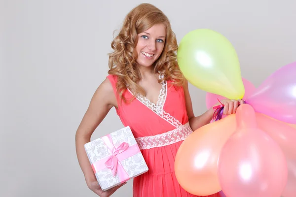 Happy woman with colourful balloons ang gift — Stock Photo, Image