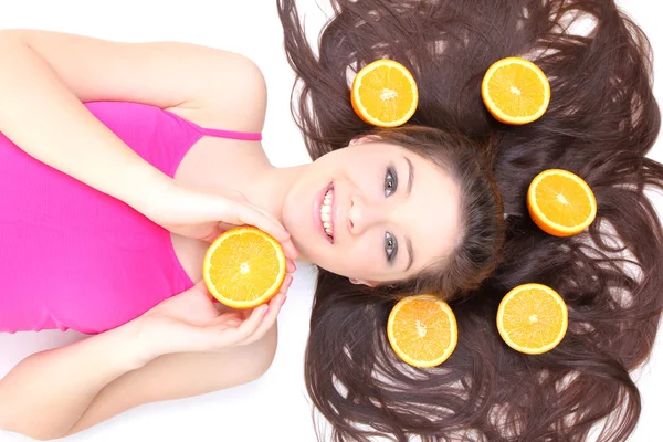 Garota feliz, deitado com pedaços de laranja — Fotografia de Stock