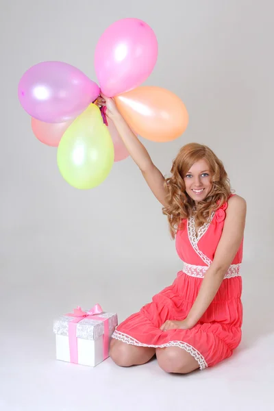 Zittend verjaardag meisje met cadeau en ballonnen — Stockfoto