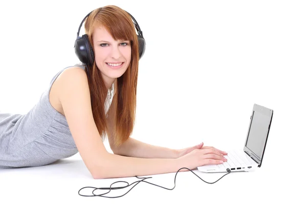 Adolescente feliz com fones de ouvido e laptop deitado — Fotografia de Stock