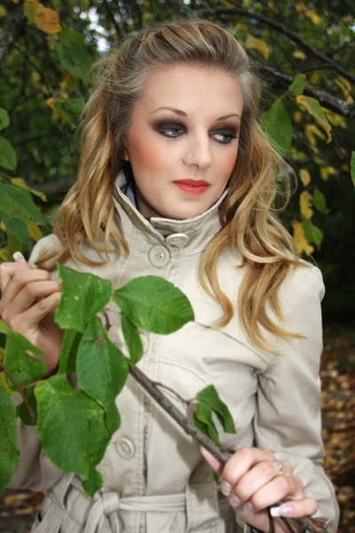 Woman in beige coat near the tree — Stok Foto