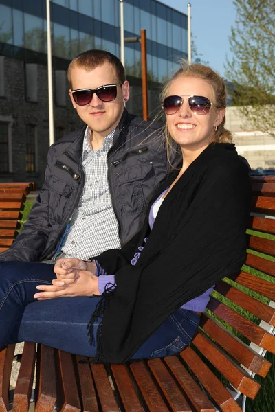 Coppia felice in occhiali da sole, seduto sulla panchina — Foto Stock