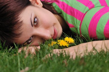 vrouw met paardebloem liggend op groen gras in de lente park