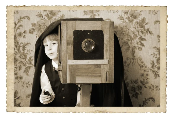 Веселый мальчик-ретро фотограф с винтажной камерой в студии — стоковое фото