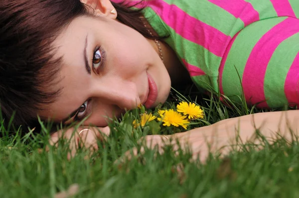 Mulher com dente de leão deitado na grama verde no parque da primavera — Fotografia de Stock