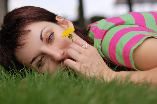 Mujer con diente de león acostada sobre hierba verde en el parque de primavera — Foto de Stock