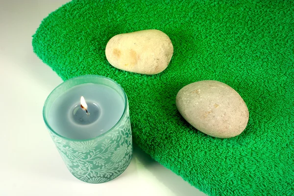Candela e pietre su asciugamano verde — Foto Stock