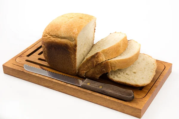 Trancher le pain blanc sur la planche à la maison avec un couteau — Photo