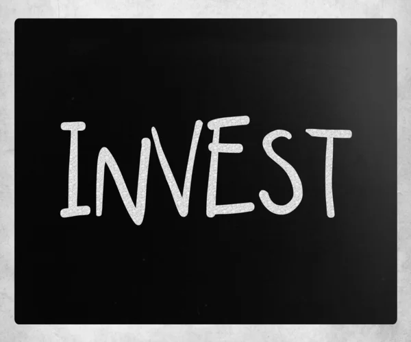 "Investir "écrit à la main à la craie blanche sur un tableau noir — Photo