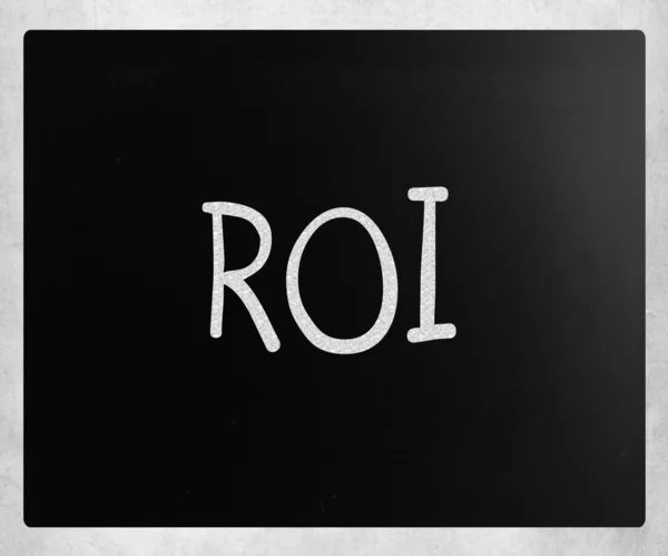 The word "ROI" handwritten with white chalk on a blackboard — Stock Photo, Image