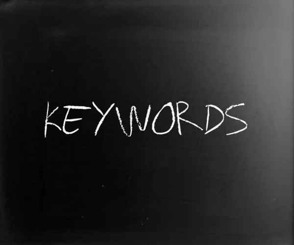 Le mot "mots clés" écrit à la main avec de la craie blanche sur un tableau noir — Photo