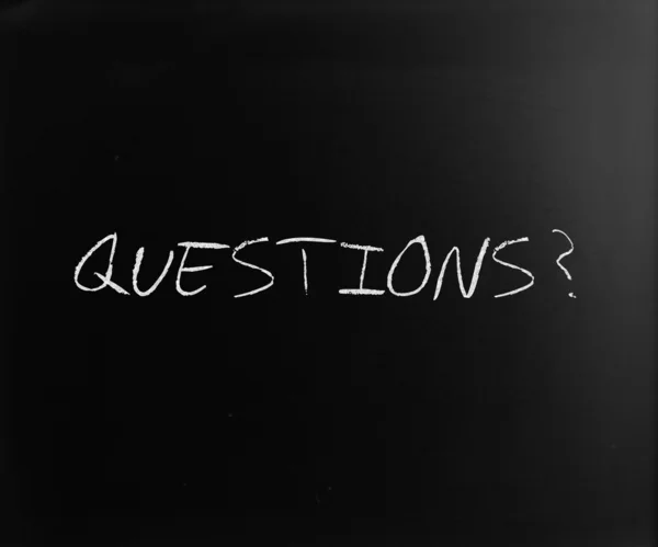 "Questions?" handwritten with white chalk on a blackboard — Stock Photo, Image