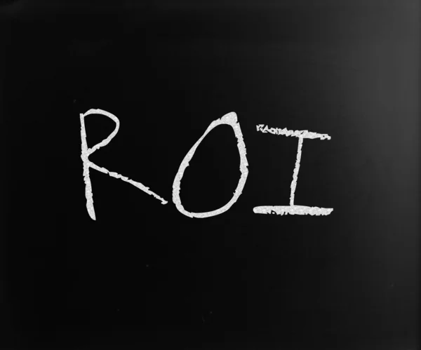 Слово "ROI" написано от руки белым мелом на доске — стоковое фото