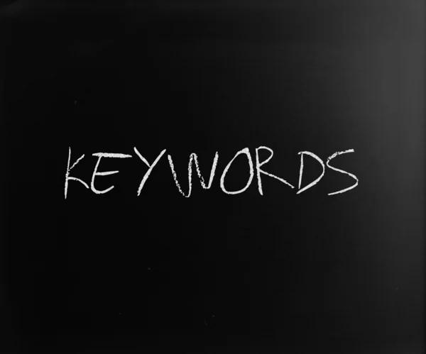 Le mot "mots clés" écrit à la main avec de la craie blanche sur un tableau noir — Photo