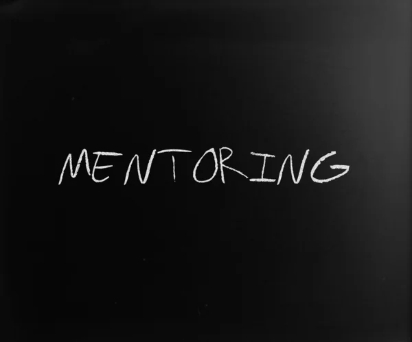 "Mentoring "handwritten with white chalk on a blackboard — стоковое фото