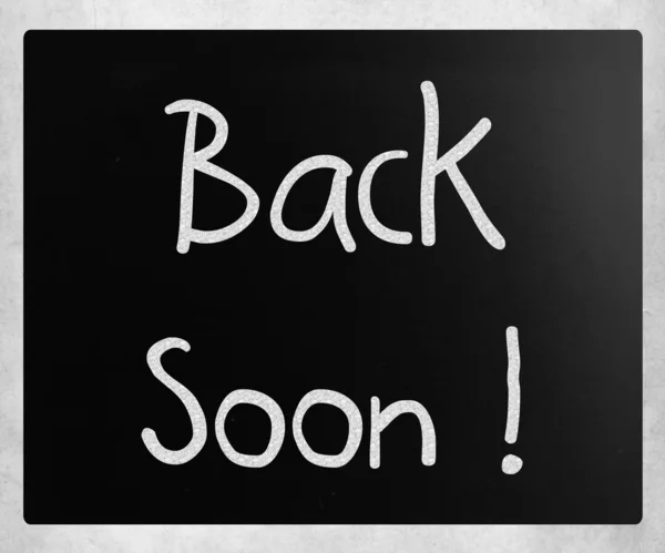 "Bientôt de retour ! " manuscrit à la craie blanche sur un tableau noir — Photo