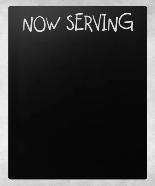 "Nu betjänar "handskriven med vit krita på en svart tavla — Stockfoto