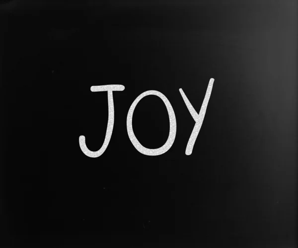 Ordet "glädjen" handskrivna med vit krita på en svart tavla — Stockfoto