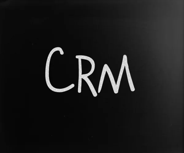用白色粉笔在黑板上手写的"crm"一词 — 图库照片