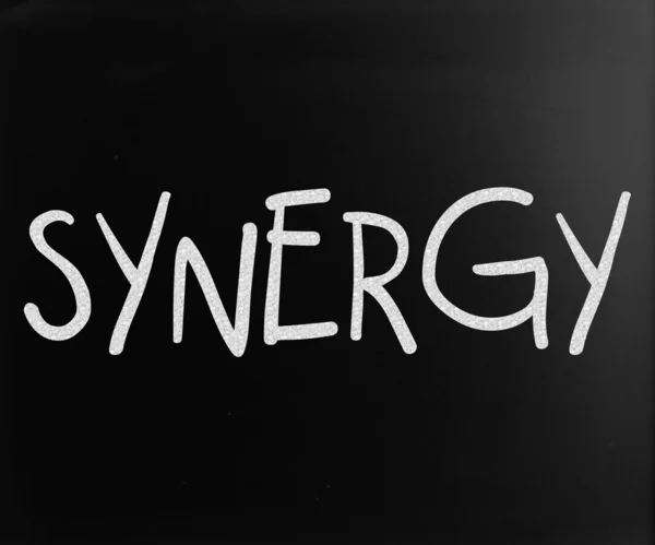 The word "Synergy" handwritten with white chalk on a blackboard — Stock Photo, Image