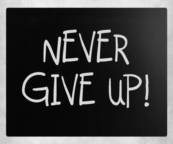 "Ne jamais abandonner "écrit à la main avec de la craie blanche sur un tableau noir — Photo