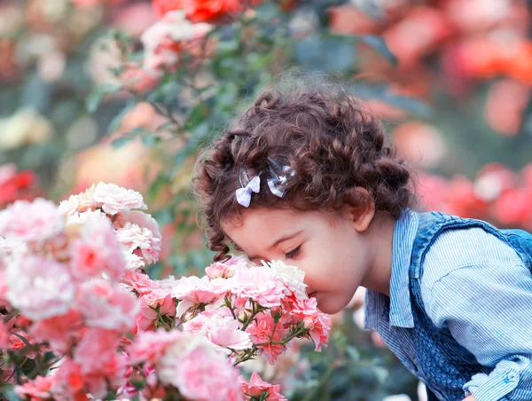 Baby girl smelling pink roses — Stock Photo, Image