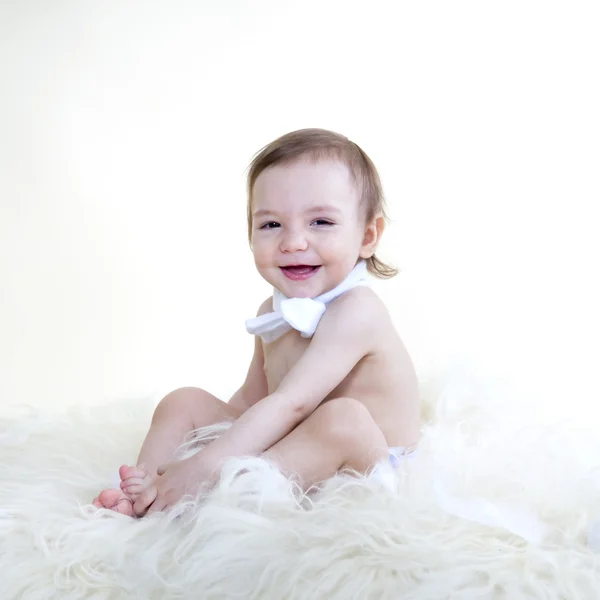 Beautiful sweet baby smiling and sitting on floor on white fur, — Stock Photo, Image