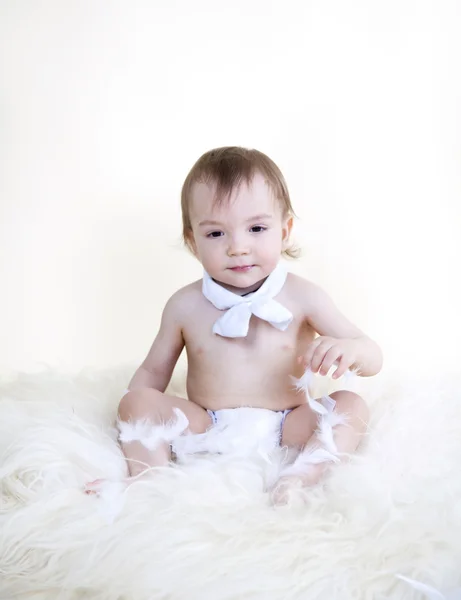 Beautiful sweet baby sitting on floor on white fur, on white bac — Stock Photo, Image