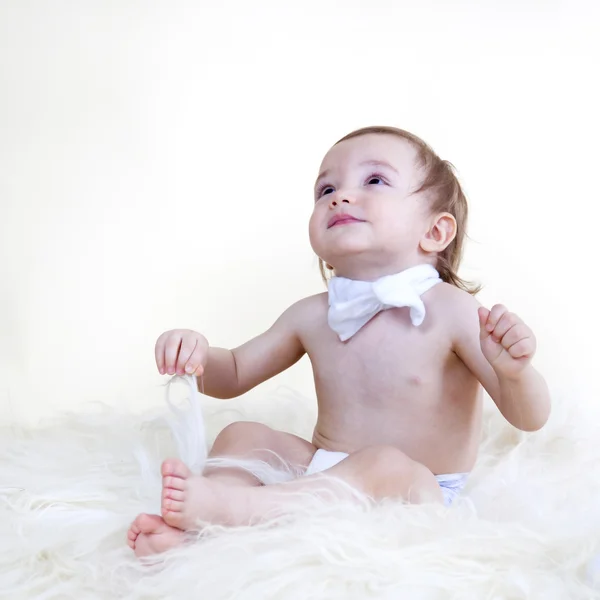 Beau bébé doux assis sur le sol en fourrure blanche, sur bac blanc — Photo