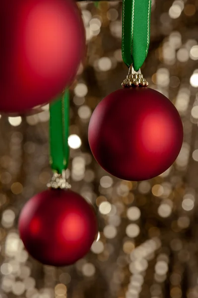 Tres adornos rojos de Navidad frente a un fondo de brillo dorado —  Fotos de Stock