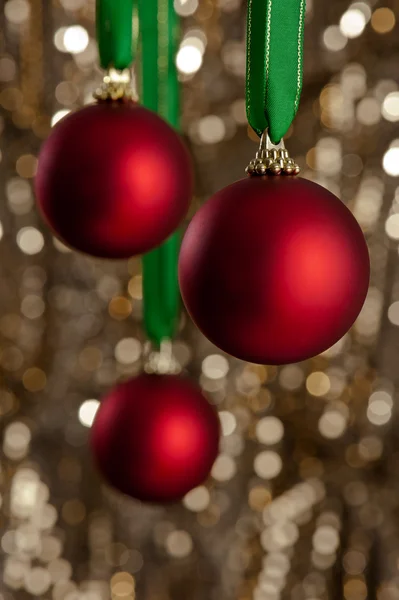 Trois boules de Noël rouges devant un backgroun de paillettes d'or — Photo