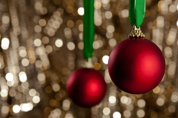 Due palline rosse di Natale davanti a uno sfondo dorato scintillante — Foto Stock