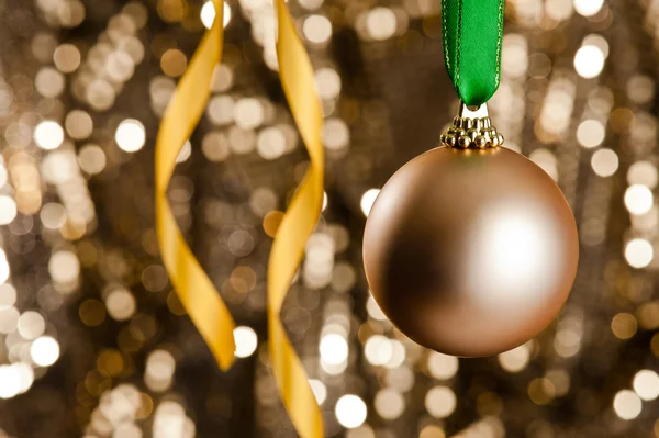 Singolo bauble di Natale d'oro davanti a un dorato glitter backgr — Foto Stock