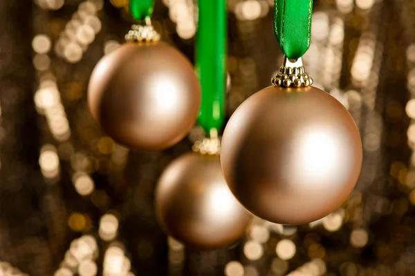 Tre palline di Natale dorate davanti a un dorato backgr glitter — Foto Stock