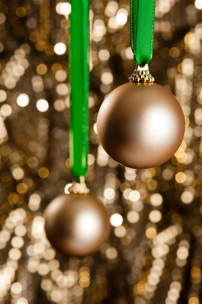 Deux boules de Noël en or devant un fond de paillettes d'or — Photo