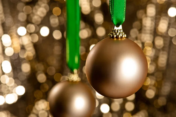 Two gold Christmas baubles in front of a gold glitter background — Stock Photo, Image