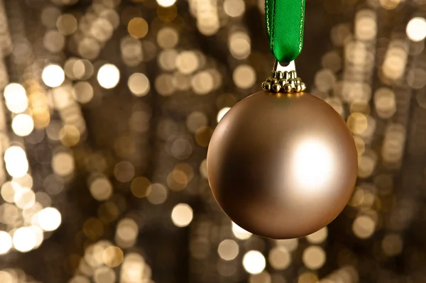 Single golden Christmas bauble in front of a gold glitter backgr — Stock Photo, Image