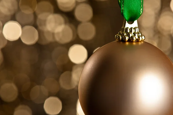 Single golden Christmas bauble in front of a gold glitter backgr — Stock Photo, Image