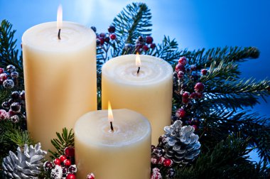 Three candles in an advent flower arrangement clipart